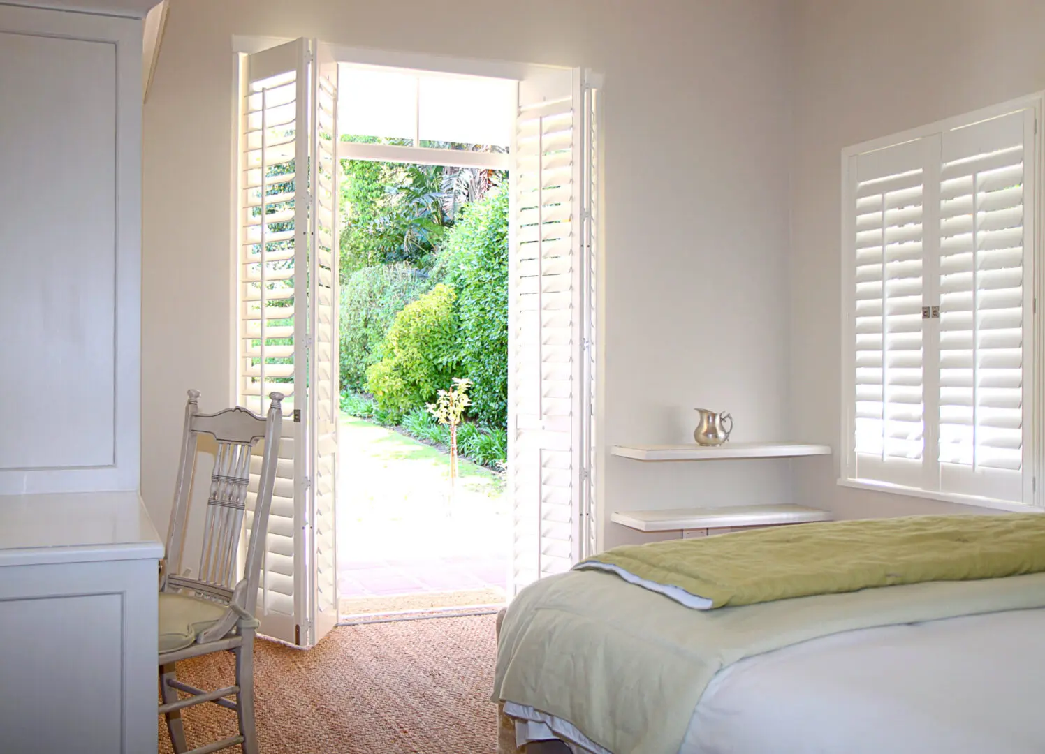 A bedroom with a bed and open door to the garden.